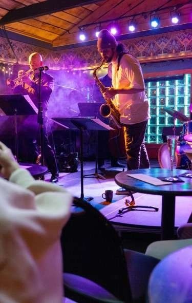 Saksofonist spiller blues på en mørklagt scene med lilla lys